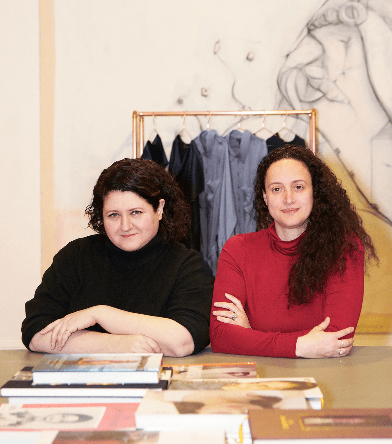 Alexandra Waldman ir Polina Veksler, inkliuzinių drabužių prekės ženklo „Universal Standard“ įkūrėjos, sėdi prie stalo su žurnalais viršuje.